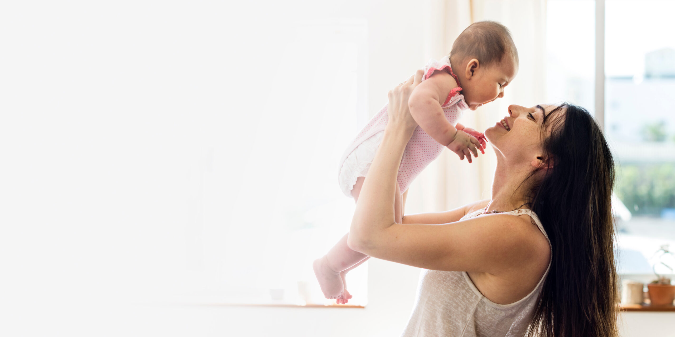 Young mom holding her baby in the air blank space